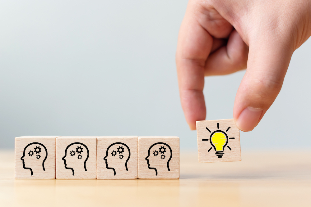 Concept creative idea and innovation. Hand picked wooden cube block with head human symbol and light bulb icon