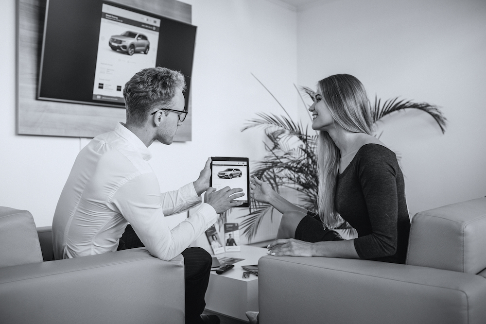 Man and woman in a car showroom using tablet
