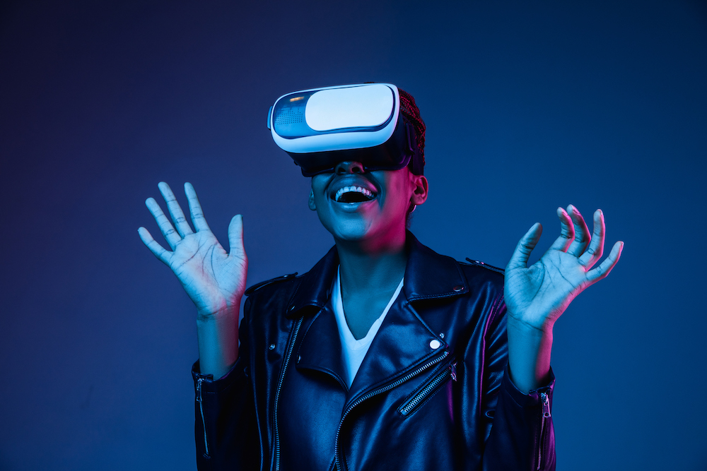 Young african-american woman’s using VR-glasses in neon light